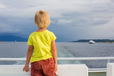Çocuk, şirin çocuk, Norveç 'te bir feribottan dağlara bakıyor.
