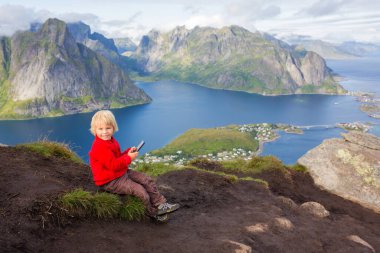 Tatlı çocuk, dağların tepesinde oturuyor ve Reinebringen Ağaç Yolu 'na tırmandıktan sonra birçok merdivenle aşağı bakıyor, Lofoten, Kuzey Norveç