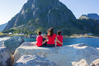 Mutlu aile, Sorvagen, Lofoten Adası, Norveç 'teki rıhtımın keyfini çıkarıyorlar. Çocuklar, güneşli bir günde kayalıklarda koşmak, güzel havanın tadını çıkarmak.