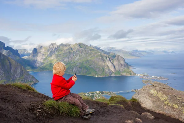 Tatlı çocuk, dağların tepesinde oturuyor ve Reinebringen Ağaç Yolu 'na tırmandıktan sonra birçok merdivenle aşağı bakıyor, Lofoten, Kuzey Norveç