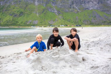 Children, playing on Ersfjords beach in Senja on a summer day, running and jumping in the sand and water, northern Norway