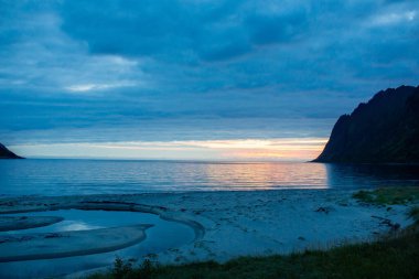 Children, enjoying sunset on Ersfjord Beach on Senja island, beautiful landscape view over the mountains, wild camping on the beach with tent and fireplace