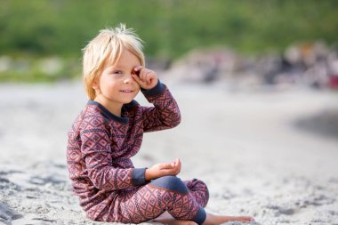 Cute toddler child, eating vitamin pills for children on the beach, child taking additional vitamins for better imunity.Kid eating alfa omega 3 child suplement vitamin pills on a holiday