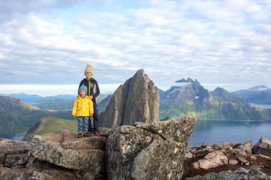 Happy family, standing on a rock and looking over Segla mountain on Senja island, North Norway. Amazing beautiful landscape and splendid nature in scandinavian country