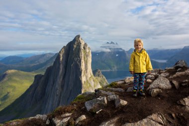 Happy family, standing on a rock and looking over Segla mountain on Senja island, North Norway. Amazing beautiful landscape and splendid nature in scandinavian country