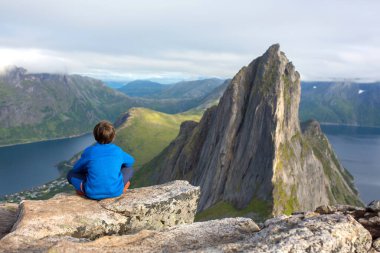 Happy family, standing on a rock and looking over Segla mountain on Senja island, North Norway. Amazing beautiful landscape and splendid nature in scandinavian country