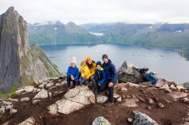 Happy family, standing on a rock and looking over Segla mountain on Senja island, North Norway. Amazing beautiful landscape and splendid nature in scandinavian country