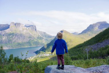 Happy family, standing on a rock and looking over Segla mountain on Senja island, North Norway. Amazing beautiful landscape and splendid nature in scandinavian country