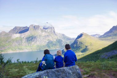 Happy family, standing on a rock and looking over Segla mountain on Senja island, North Norway. Amazing beautiful landscape and splendid nature in scandinavian country
