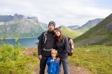 Happy family, standing on a rock and looking over Segla mountain on Senja island, North Norway. Amazing beautiful landscape and splendid nature in scandinavian country