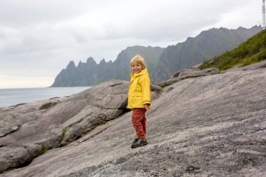 Çocuk, Tungeneset, Senja, Norveç 'te küçük çocukla eğleniyor, büyük su birikintisinin üzerinden atlıyor, suda yansıtıyor.