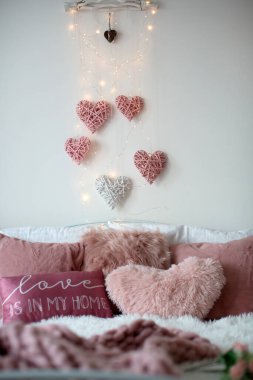 Love sign and valentine decorated bed with pillows, hearts and lights, stylish decoration