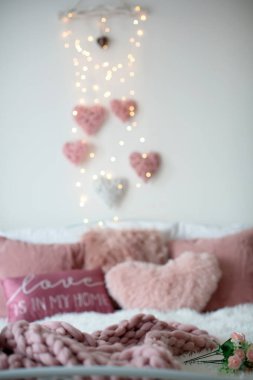 Love sign and valentine decorated bed with pillows, hearts and lights, stylish decoration