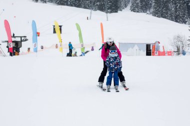Güzel genç anne ve onun okul öncesi çocuk, dağlarda, kış Kayak