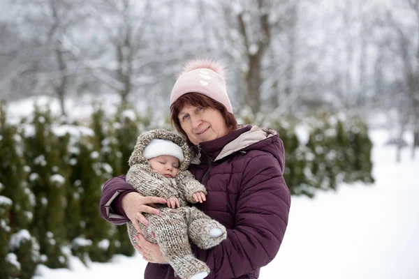 Karlı bir kış gününde küçük bir çocuğu kucağında tutan büyükannenin portresi çekiliyor.