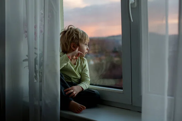 Blond Maluch Dziecko Siedzi Oknie Zachodzie Słońca Patrząc — Zdjęcie stockowe