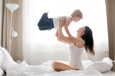 Güzel sarışın çocuk ve annesi, sabahları evde oynuyorlar, gülüyorlar, gülüyorlar ve birlikte eğleniyorlar.