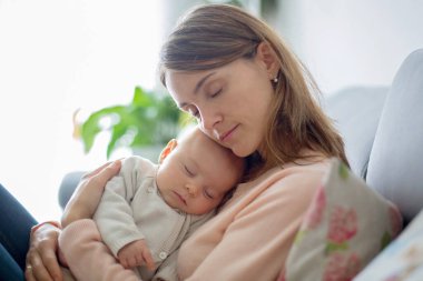 Genç anne, şefkatle kucağında yeni doğmuş bebeğini, yakın bir portre