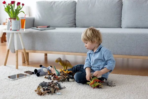 かわいい金髪の子供 幼児の男の子 恐竜と家で遊んで 床に座って — ストック写真