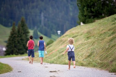 İsviçre 'de mutlu bir aile, dağda küçük bir yolda yürüyor, yaz tatiline çıkıyor.
