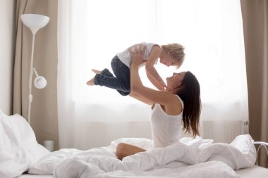 Güzel sarışın çocuk ve annesi, sabahları evde oynuyorlar, gülüyorlar, gülüyorlar ve birlikte eğleniyorlar.