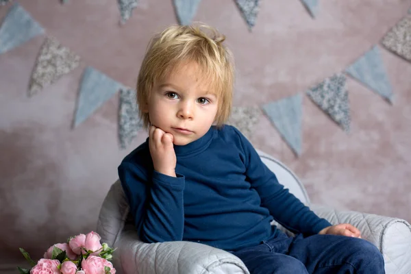 可爱的金发碧眼的小孩 坐在小婴儿扶手椅上 捧着花 室内拍摄 — 图库照片
