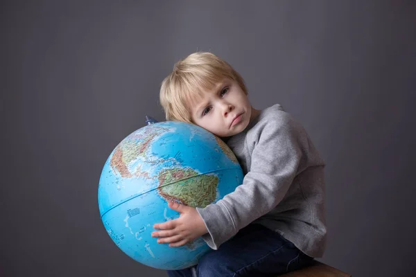 Cute toddler child, boy, hugging big globe, isolated image