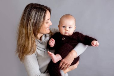 Genç anne, yeni doğmuş bebeğini okşuyor, onu kollarına alıyor, farklı pozisyonlarda bebeği tutuyor, mutluluktan gülümsüyor.