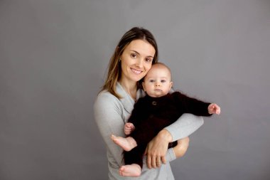 Genç anne, yeni doğmuş bebeğini okşuyor, onu kollarına alıyor, farklı pozisyonlarda bebeği tutuyor, mutluluktan gülümsüyor.