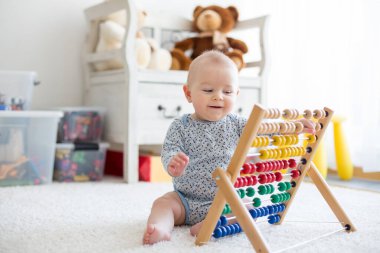 Sevimli küçük oğlan, evde abaküsle oynuyor, güneşli çocuk odası.