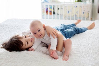 Küçük çocuk, yatak odasında küçük kardeşiyle oynuyor.