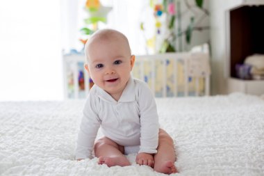 Evde yatak odasında yatakta peluş oyuncak ile oynarken küçük oğlu, yürümeye başlayan çocuk,