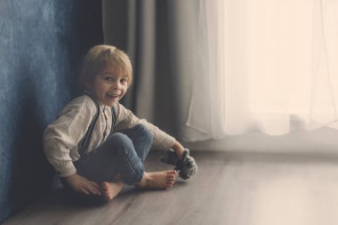 Sevimli sarışın anaokulu çocuğu, evcil köpekle yerde oturuyor, yaramazlık yaptığı için cezalandırılıyor, anneme kızgın.