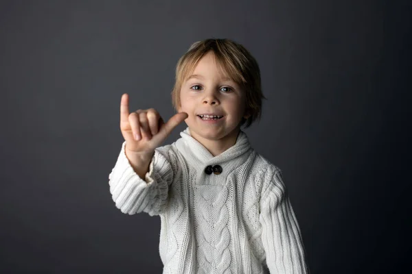 かわいい幼児の男の子 灰色の背景に手話でジェスチャーを示す 孤立した画像 手の歌を示す子供 — ストック写真