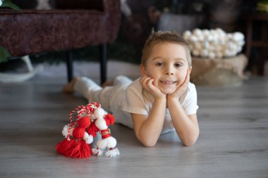 Tatlı çocuk, sarışın çocuk, beyaz ve kırmızı bileklikle oynayan, Bulgar martenitsa