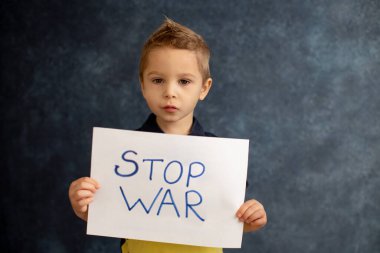 Genç sarışın çocuk, barışa destek işareti taşıyor, savaş yok, çocuk huzurlu bir hayat diliyor. Görüntü Ukrayna 'da devam eden savaşla bağlantılı