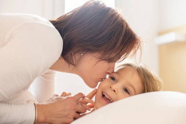 Anne ve çocuk, sarışın çocuk, sabahları yatakta sarılıyor, sevgi ve şefkat, aile zamanı.