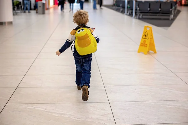 Preschool child, running at the airport to the gate, late for boarding to flight in airport transit hall near departure gate. Active family lifestyle travel by air with child on vacation
