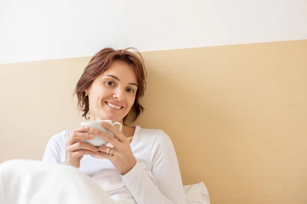 Vrouw Morgens Bed Koffie Drinkend Lachend Naar Camera — Stockfoto