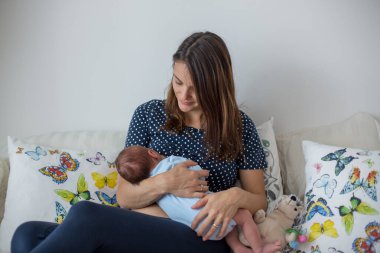 Genç anne yeni doğmuş bebeğini evde emziriyor.