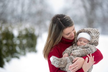 Güneşli bir kış gününde güzel anne ve bebek bebek tulumlarını giyip, güzel kış portrelerini çektiler.