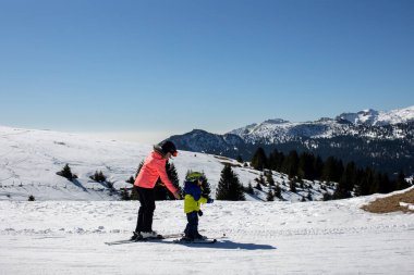 Mutlu bir aile, güneşli bir günde İtalya 'da kayak, çocuklar ve yetişkinler birlikte kayak yapıyor. Aile tatili