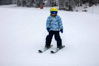 Renkli kayak kıyafetli şirin bir çocuk güneşli bir günde İtalya 'da kayak yapıyor, çocuklar ve yetişkinler birlikte kayak yapıyor. Aile tatili