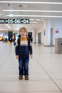Havalimanı geçiş koridorunda kalkış kapısında bekleyen sevimli bir oğlan çocuğu. Aktif aile hayatı tatilde çocukla hava yoluyla seyahat