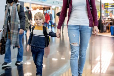 Havalimanı geçiş koridorunda kalkış kapısında bekleyen sevimli bir oğlan çocuğu. Aktif aile hayatı tatilde çocukla hava yoluyla seyahat
