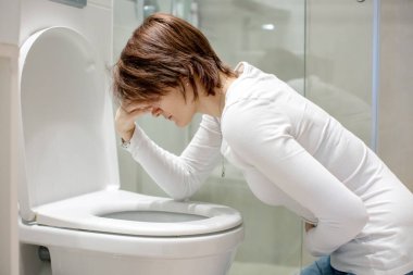Woman, girl, experiencing sickness, vomiting, pregnancy, poisoning and morning discomfort, sitting over the toilet clipart
