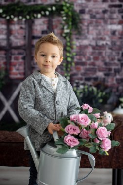 Şirin bir çocuk, beyaz gömlekli bir çocuk, Paskalya süslemesinde yumurta ve çikolatalı tavşanla oynuyor, stüdyo fotoğrafı.