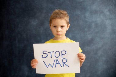 Genç sarışın çocuk, barışa destek işareti taşıyor, savaş yok, çocuk huzurlu bir hayat diliyor. Görüntü Ukrayna 'da devam eden savaşla bağlantılı