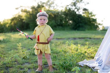 Kostümleri ile yerli Amerikan erkek sevimli portre, gün batımında balta ile parkta açık oynarken, yaz