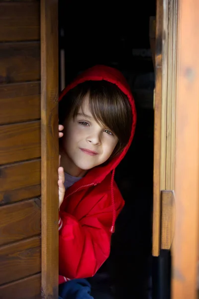 赤いスウェットシャツを着た十代の少年 木製のドアの後ろに隠れ 怖くて悲しそうに見える — ストック写真